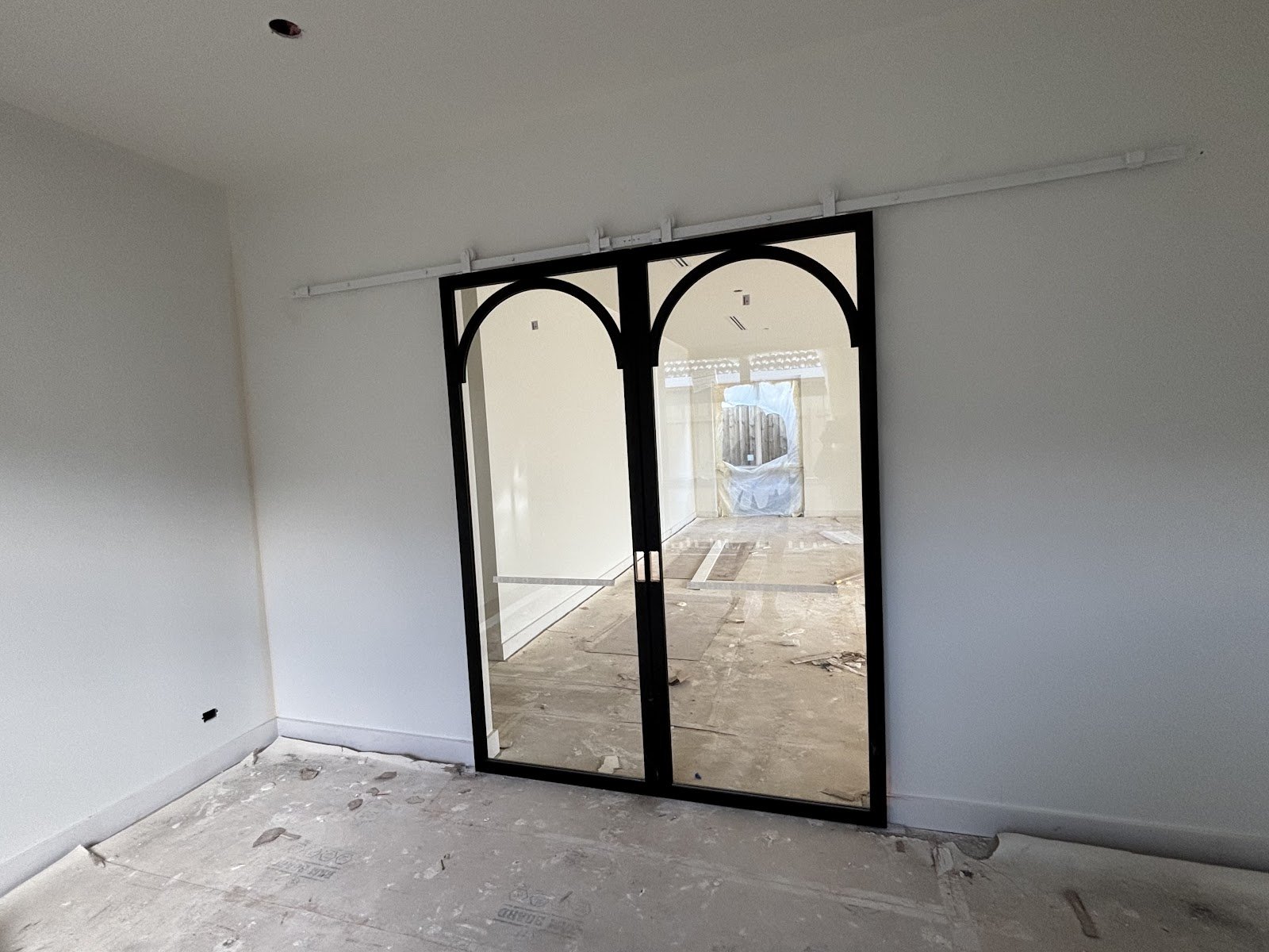 Black steel-framed arched glass sliding doors installed during a home renovation