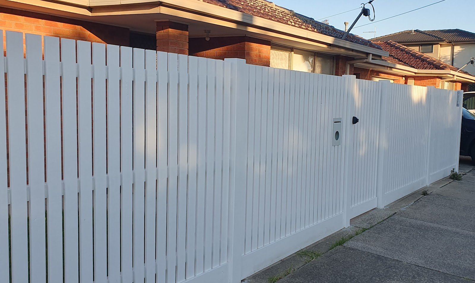 White picket fence and gates built by Trev's Carpentry & Renovations in front of a brick home in Altona